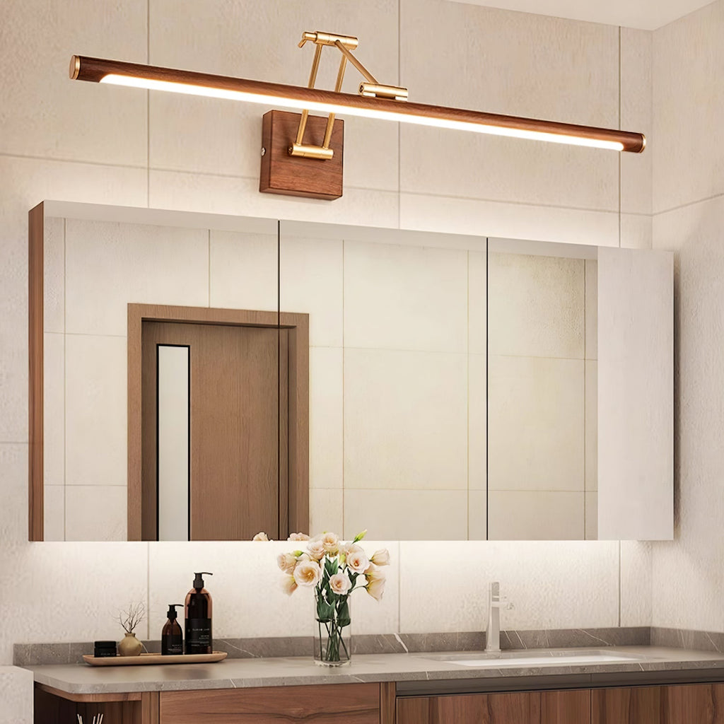 Lit above a mirrored cabinet and a wooden door reflection, this Clérachic linear wall light sits over a vanity with a vase of flowers.