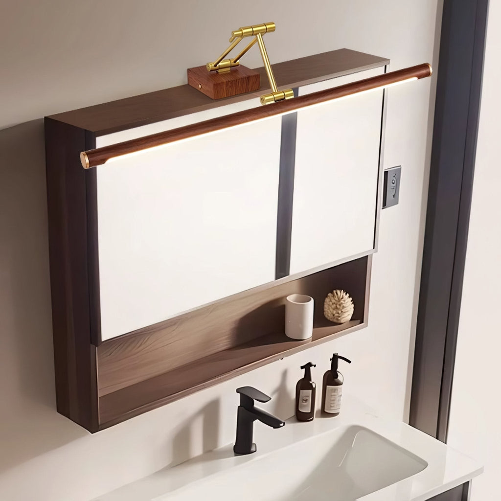 This Clérachic linear wall light mounted on top of a dark wooden mirror cabinet, above a black tap, soap bottles and a white basin.