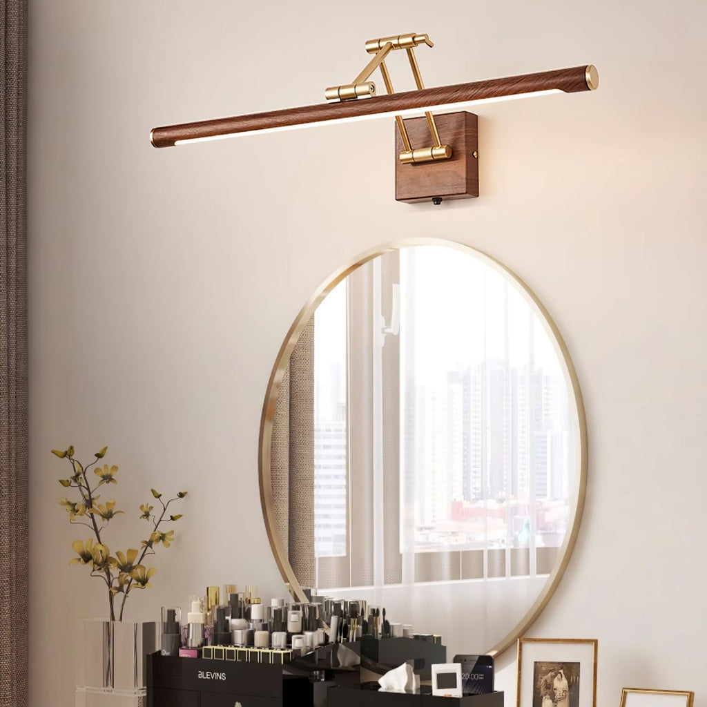 This Clérachic linear wall light lit above a round gold-framed mirror, with a dressing table of make-up and dried stems below.