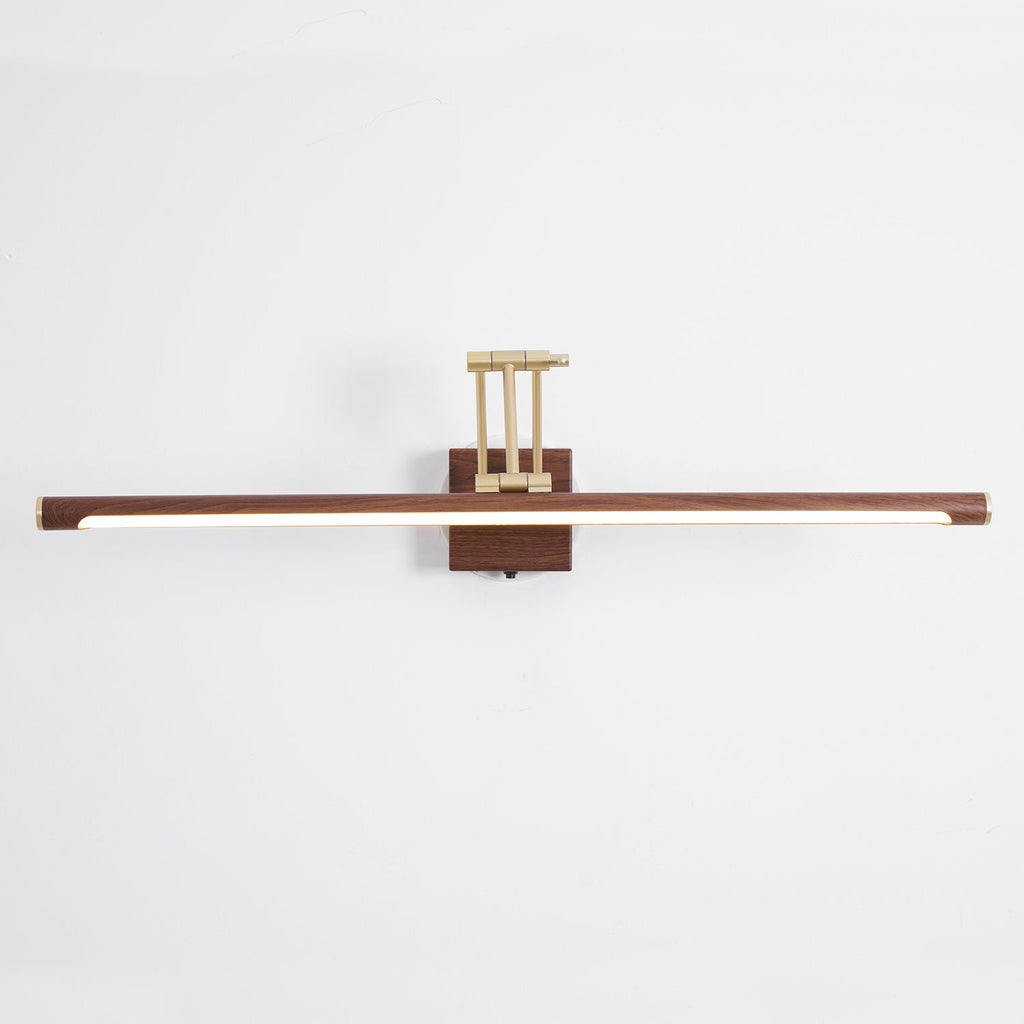 Front view of this Clérachic linear wall light on a pale wall, with its walnut tube lit along the underside and a brass arm above.
