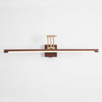 Front view of this Clérachic linear wall light on a pale wall, with its walnut tube lit along the underside and a brass arm above.
