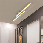 Clérachic gold twin-bar ceiling light with frosted diffusers, running along a hallway ceiling beside a black glass wardrobe.
