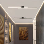 Two Clérachic black twin-bar ceiling lights in a hallway with cove lighting, gold wall art and small up-down wall lights.