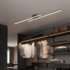Clérachic black twin-bar ceiling light with frosted diffusers, above an open dressing area with hanging shirts and shelving.