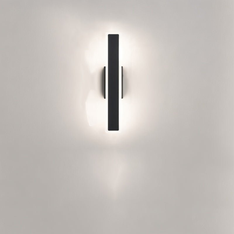 Clérachic short black aluminium bar light mounted vertically on a pale wall, its frosted diffuser giving a soft halo of light.