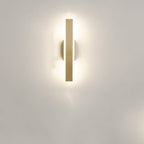 Clérachic short gold aluminium bar light mounted vertically on a pale wall, its frosted diffuser giving a soft halo of light.
