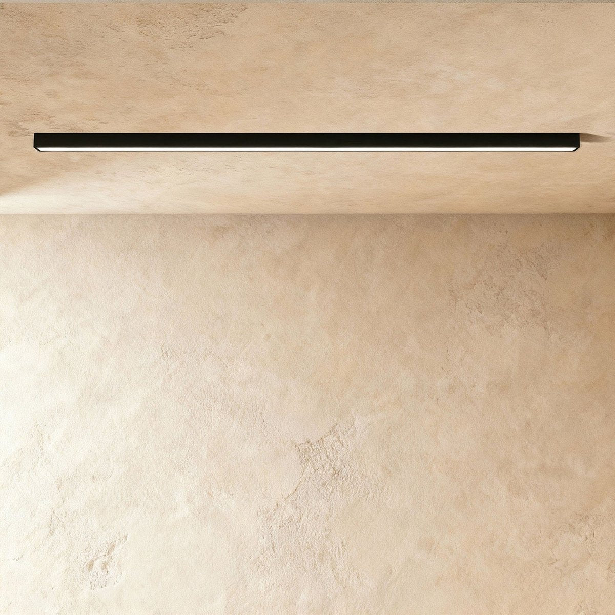 A black linear LED ceiling bar shows its continuous lit strip flush against a plaster ceiling corner, a Clérachic kitchen island light.