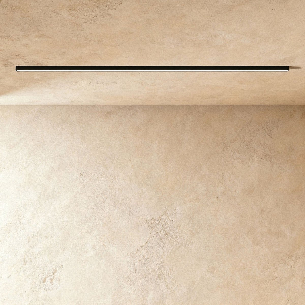 A black linear LED ceiling bar throws a clean lit line onto a warm plaster corner, this Clérachic fixture framed from further back.