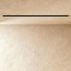 A black linear LED ceiling bar sits lit flush in a ceiling corner, this Clérachic fixture shown against a softly textured plaster wall.