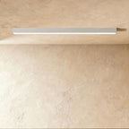 A soft white linear LED ceiling bar glows a continuous line in a plaster corner, this Clérachic fixture seen from below, unlit finish pale.