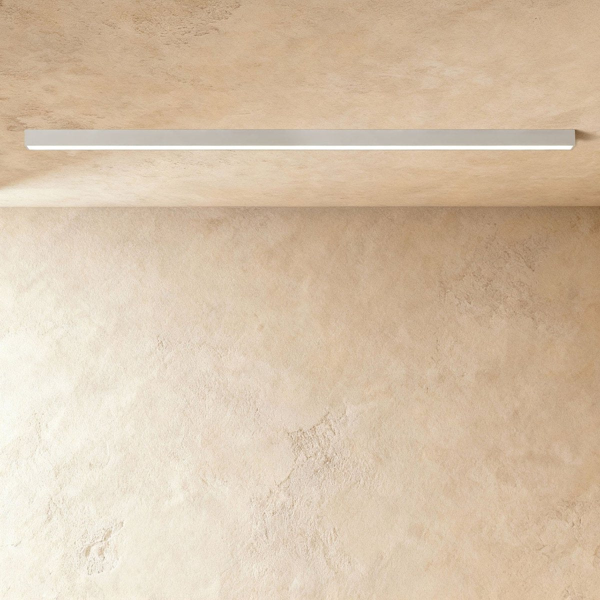 A soft white linear LED ceiling bar shows its lit strip flush against a plaster ceiling corner, a Clérachic kitchen island light.