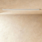 A soft white linear LED ceiling bar, lit edge to edge, sits flush where a plaster ceiling meets the wall, this Clérachic fixture in view.