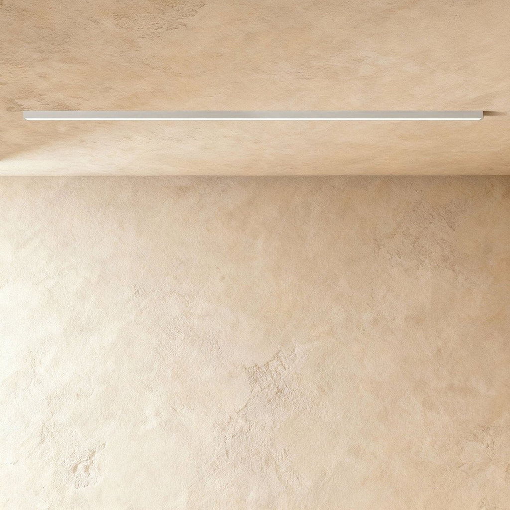 A soft white linear LED ceiling bar throws a clean lit line onto a plaster corner, this Clérachic fixture framed from further back.