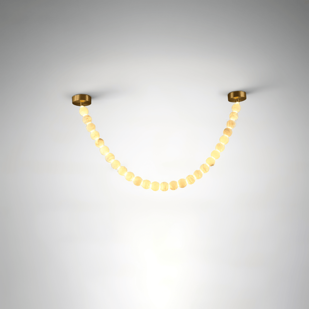 The Clérachic alabaster bead strand chandelier in single-strand form, warm LED glowing through a gold-mounted bead garland.