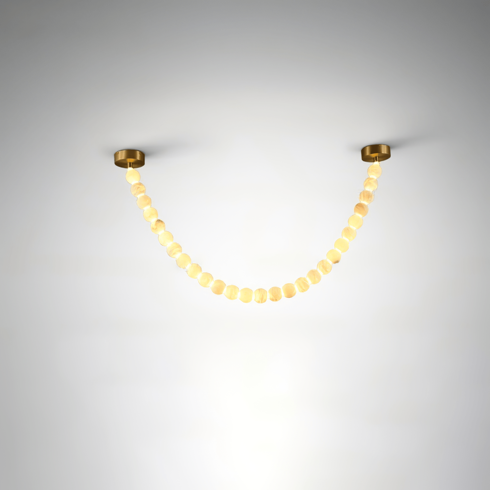 The Clérachic alabaster bead strand chandelier in single-strand form, warm LED glowing through a gold-mounted bead garland.