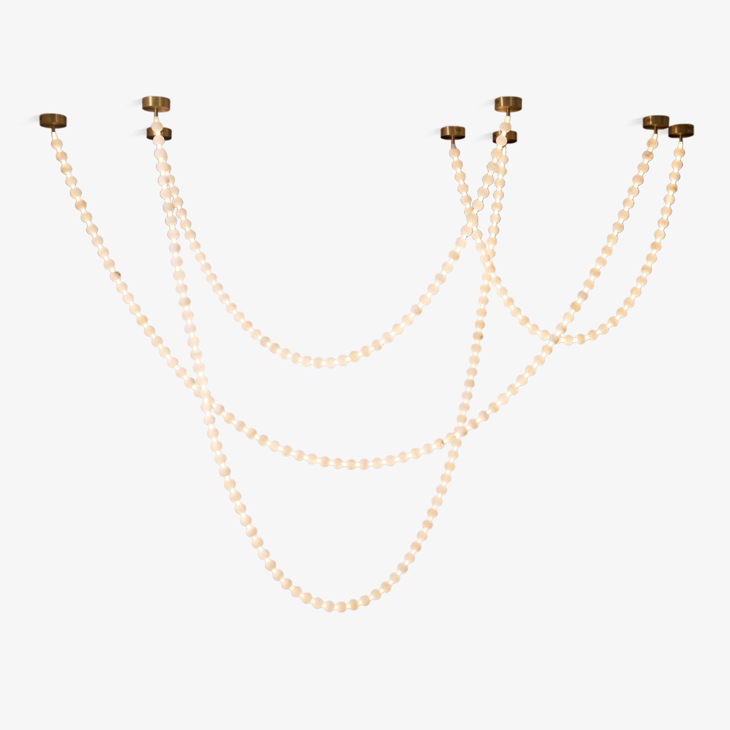 Four strands of the Clérachic alabaster bead chandelier cascade side by side from separate gold ceiling mounts.