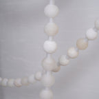 Macro view of individual alabaster beads on the Clérachic chandelier, showing the natural stone's veining and pale tone.