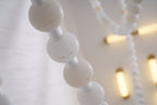 Close-up of the Clérachic alabaster bead chandelier's stone beads, softly lit with warm ceiling mounts blurred behind.