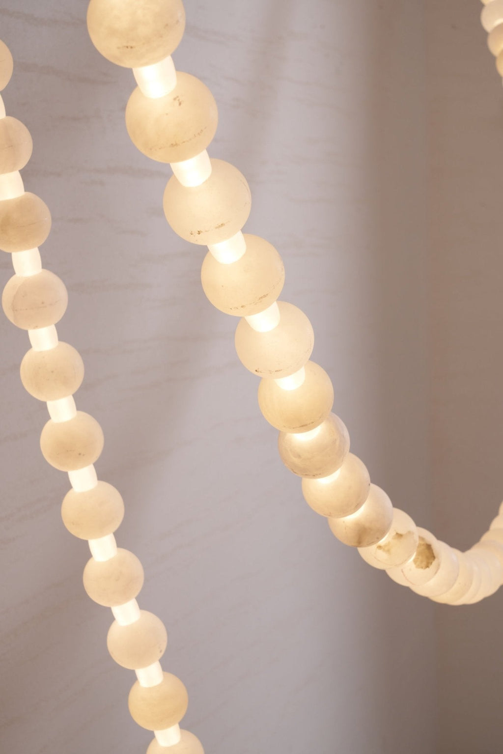 Detail of pale alabaster beads on the Clérachic chandelier's gold frame, unlit to show the stone's natural texture.
