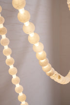 Detail of pale alabaster beads on the Clérachic chandelier's gold frame, unlit to show the stone's natural texture.