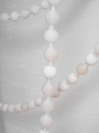 Close-up of a lit alabaster strand on the Clérachic chandelier, with a second strand and gold mounts soft-focused behind.