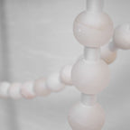 Macro shot of the Clérachic alabaster bead chandelier's LED glowing warmly through the stone beads along the strand.