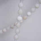 Detail of unlit alabaster beads on the Clérachic chandelier, crossing strands showing the stone's varied pale tones.