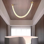 A single strand of the Clérachic alabaster bead chandelier lights a wood-paneled hallway ceiling above a curved reception desk.