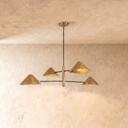 Clérachic linear chandelier in a brighter satin brass, four cone shades branching from crossed arms on the ceiling.