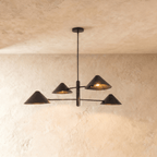 Clérachic linear chandelier in matte black, four angled cone shades on crossed arms mounted to the ceiling.