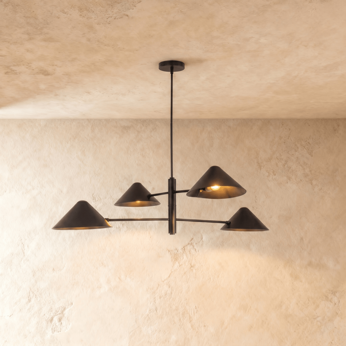 Clérachic linear chandelier in matte black, four angled cone shades on crossed arms mounted to the ceiling.