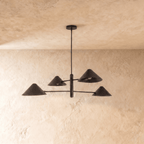Clérachic four-arm linear chandelier in matte black, a closer view of the crossed arms and cone shades overhead.