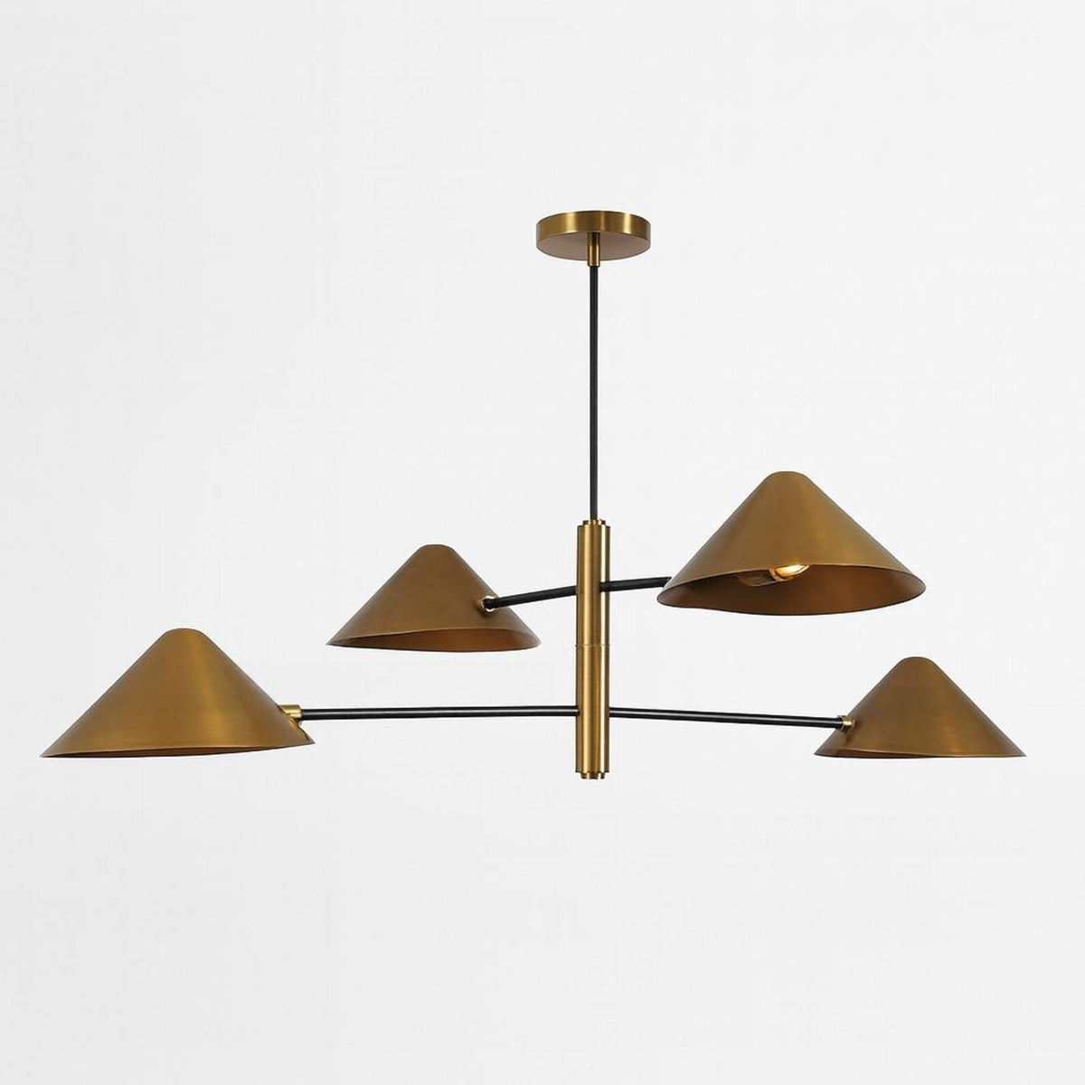 Clérachic linear chandelier with four brushed brass cone shades on slim black arms, photographed against a pale studio wall