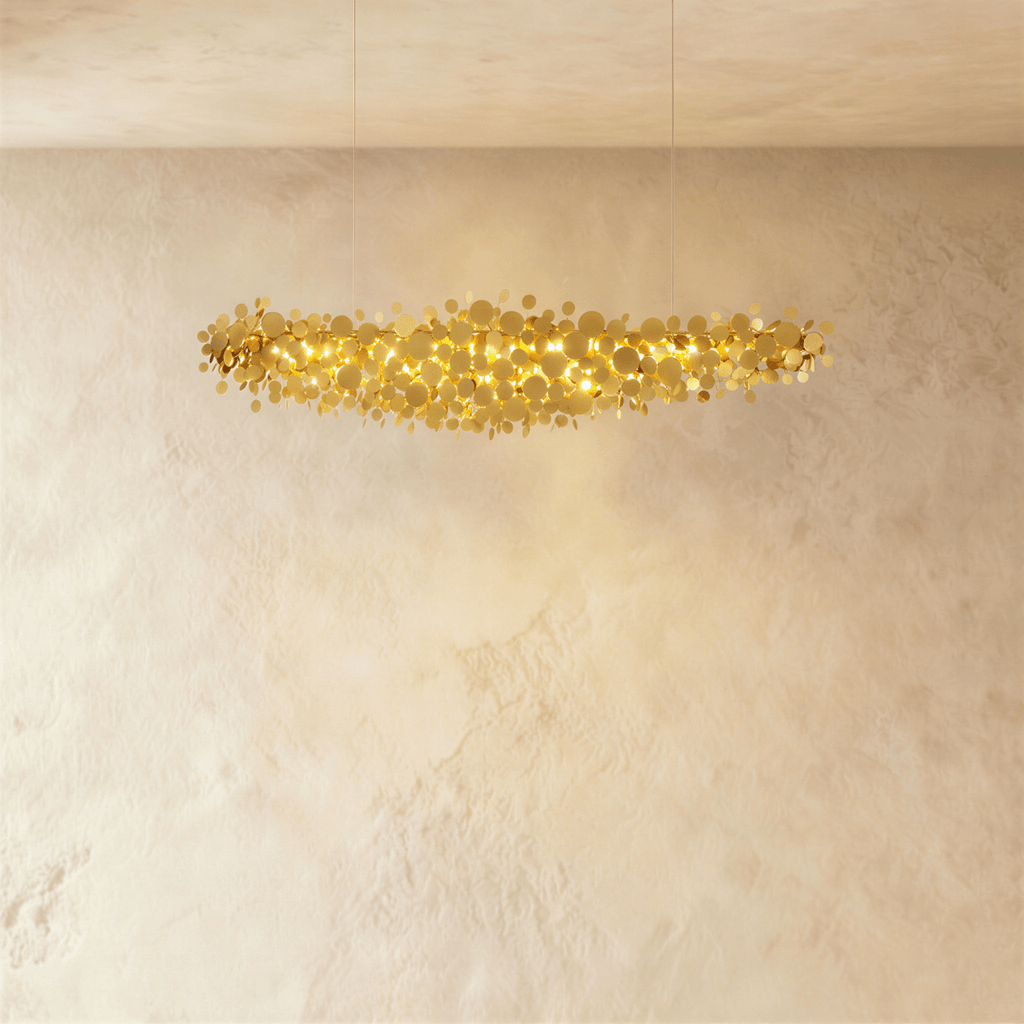Clérachic shorter gold disc chandelier suspended on two thin cables, its warm light spilling over a textured plaster wall.