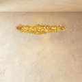 Clérachic shorter gold disc chandelier suspended on two thin cables, its warm light spilling over a textured plaster wall.