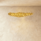 Clérachic shorter gold disc chandelier suspended on two thin cables, its warm light spilling over a textured plaster wall.