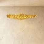 Clérachic mid-length gold disc chandelier with a cloud of overlapping metal discs lit from within, on a limewash wall.