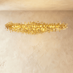 Clérachic longest gold disc chandelier spanning the frame, hundreds of metal discs glowing warm against limewash.