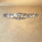 Clérachic longest chrome disc chandelier, a wide cloud of mirrored discs lit warm against a plaster wall.