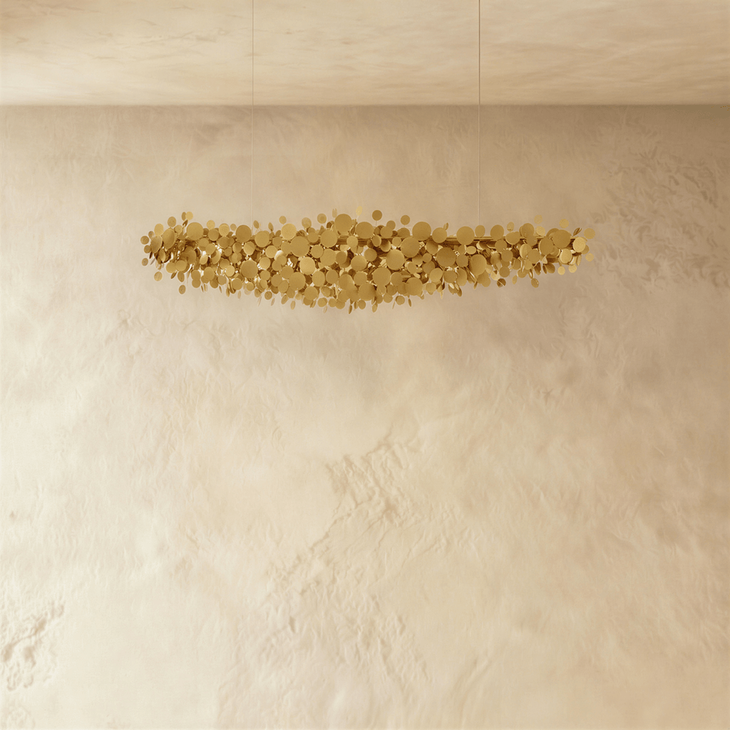 Clérachic gold disc chandelier shown unlit, the brushed metal discs forming a loose cloud against a plaster wall.