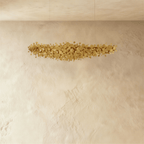 Clérachic gold disc chandelier shown unlit, the brushed metal discs forming a loose cloud against a plaster wall.