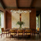 Clérachic chrome disc chandelier over a long walnut dining table, set against a panelled wall and large artwork.