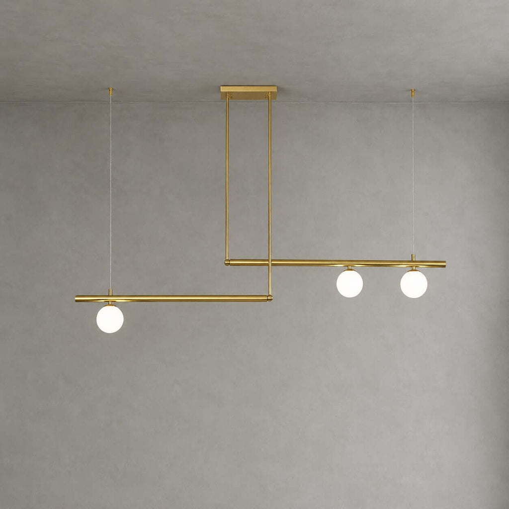 Offset brass bars, one carrying a single frosted globe and the other two, on this Clérachic chandelier against a plain grey wall.