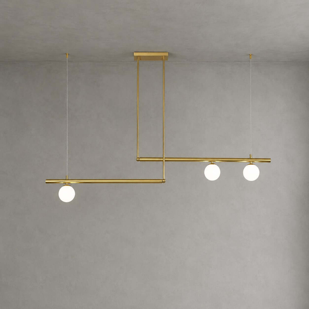 Offset brass bars, one carrying a single frosted globe and the other two, on this Clérachic chandelier against a plain grey wall.