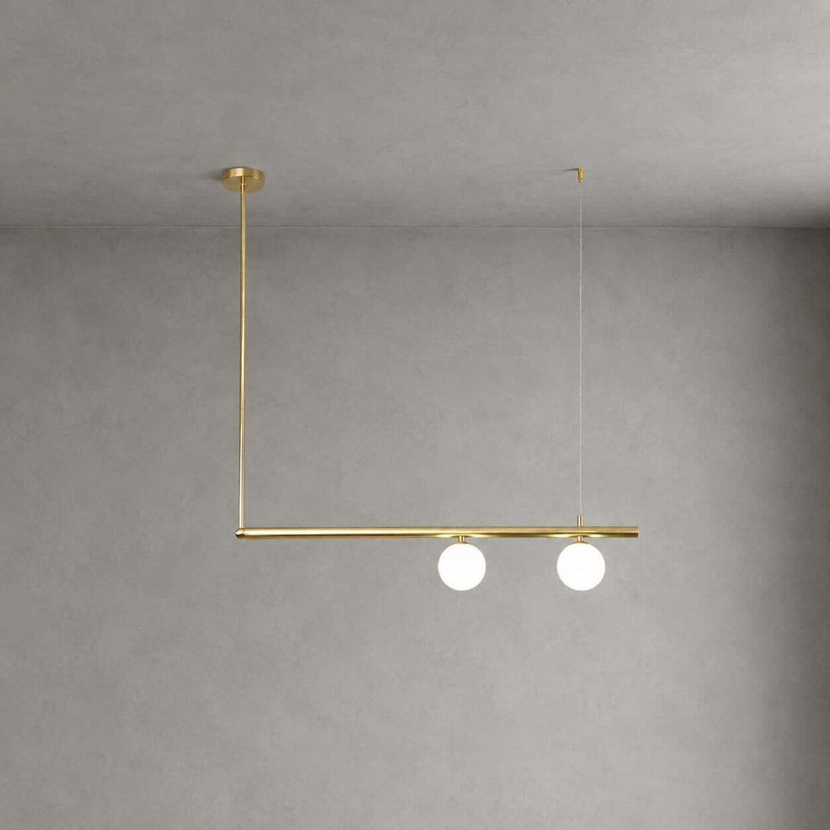 Clérachic chandelier with a single brass bar, two lit frosted globes and an L-shaped drop from a round canopy, on a grey wall.