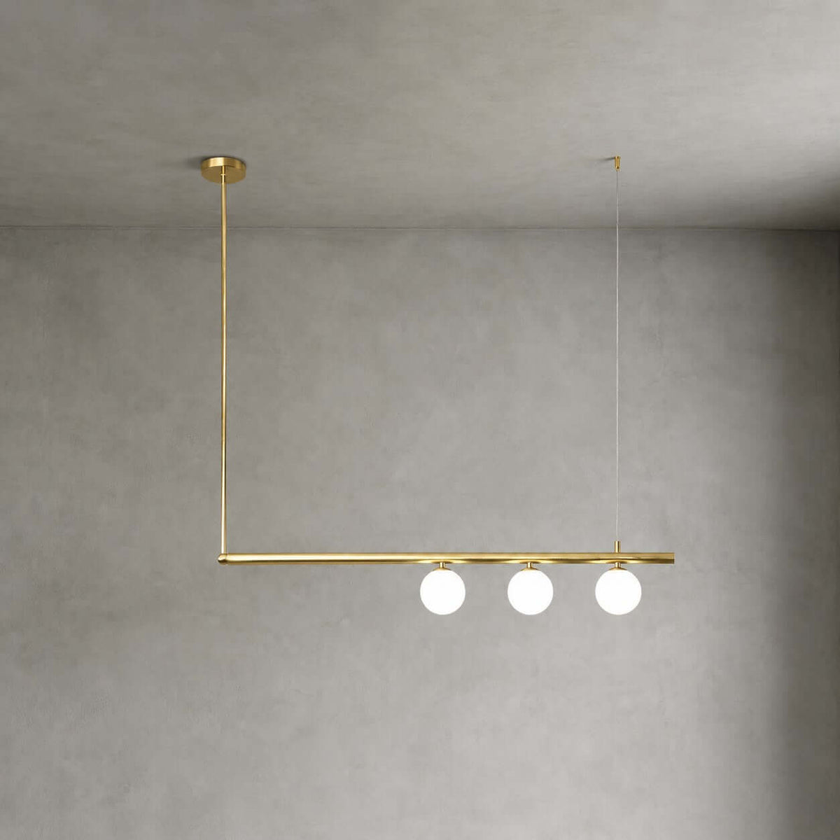 Three frosted globes under one brass bar, hung from a round canopy on this Clérachic chandelier, against a concrete-look wall.