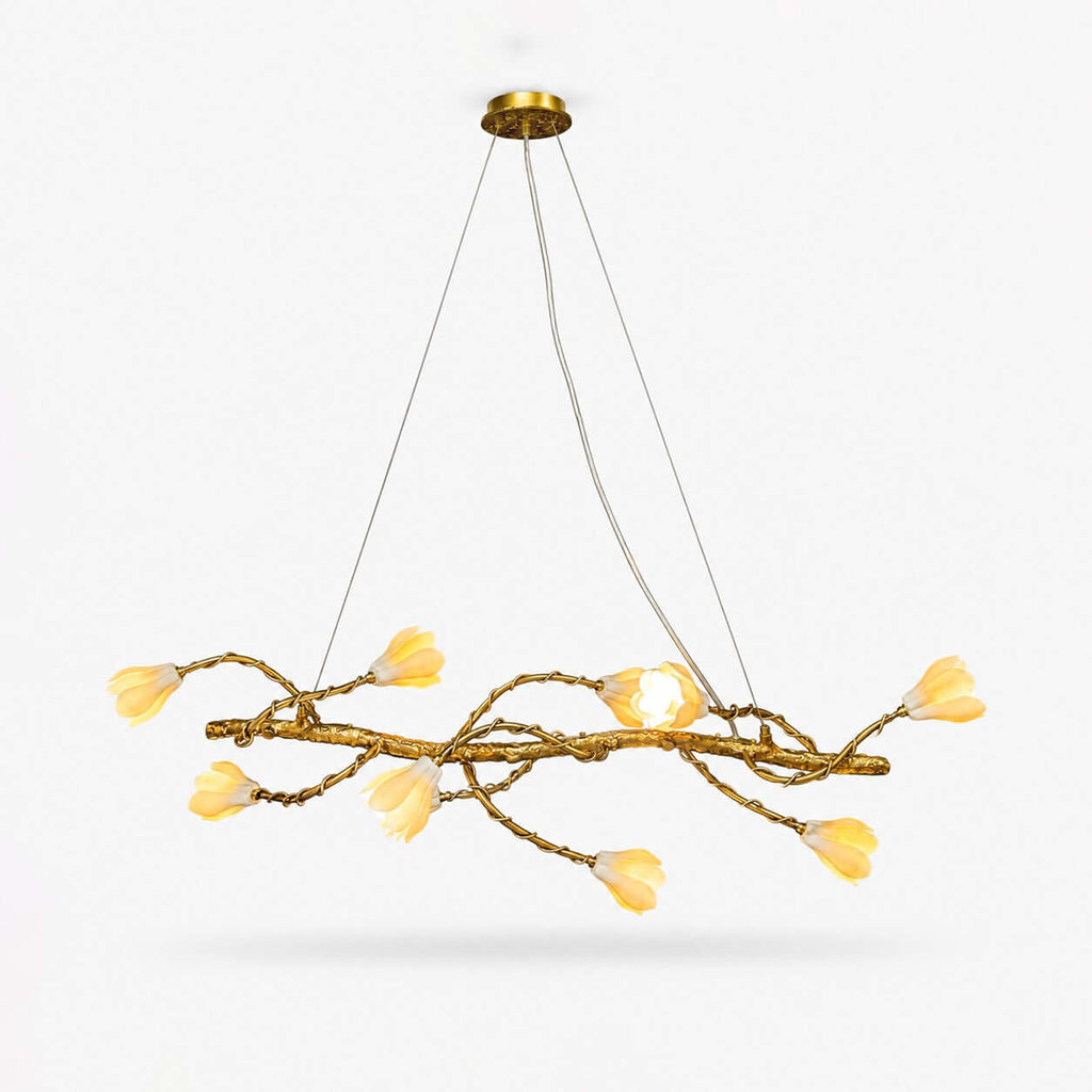 Linear branch chandelier from Clérachic, a gold-tone twisting vine with ten cream ceramic magnolia blooms, on a plain white backdrop.