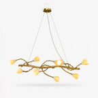Linear branch chandelier from Clérachic, a gold-tone twisting vine with ten cream ceramic magnolia blooms, on a plain white backdrop.