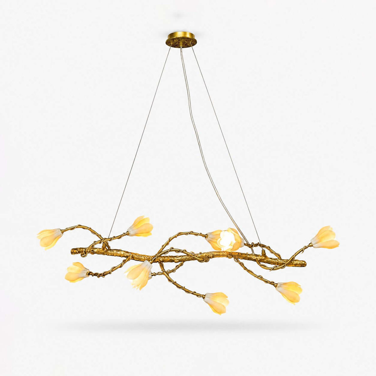 Linear branch chandelier from Clérachic, a gold-tone twisting vine with ten cream ceramic magnolia blooms, on a plain white backdrop.
