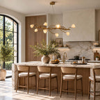 A Clérachic vine chandelier with ceramic magnolia blooms above a marble-topped kitchen island with woven counter stools.